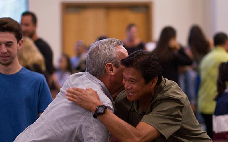 Men embracing in room of people